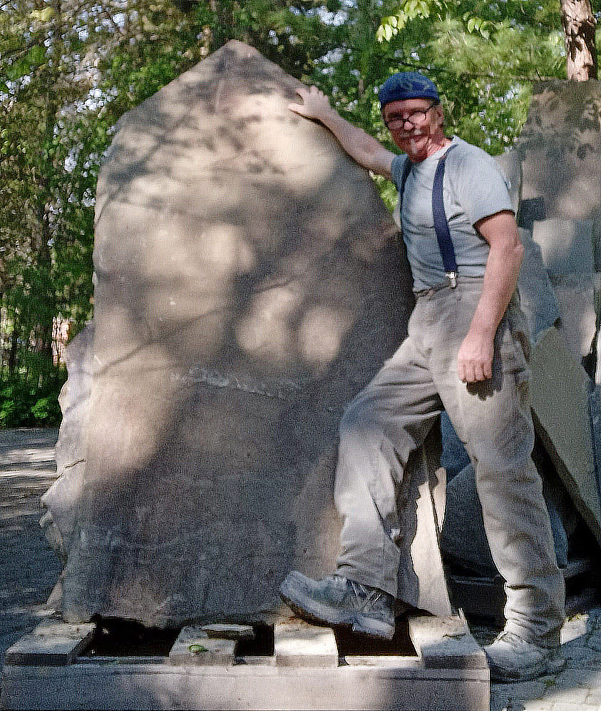 Chris Beaudry with a large stone, ready to work on it, a photo